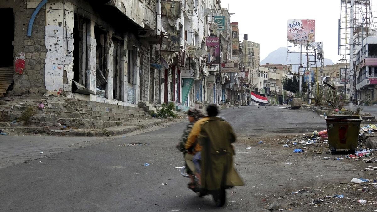 Men ride through streets wrecked by fighting in Taiz, Yemen.- AP
