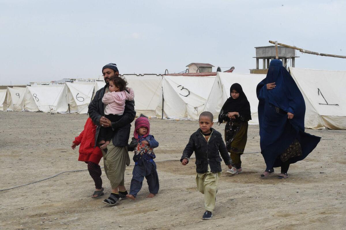 Afghan refugees walk near tents at a temporarily camp as they wait to cross the Pakistan-Afghanistan border in Chaman on November 7, 2023. — AFP