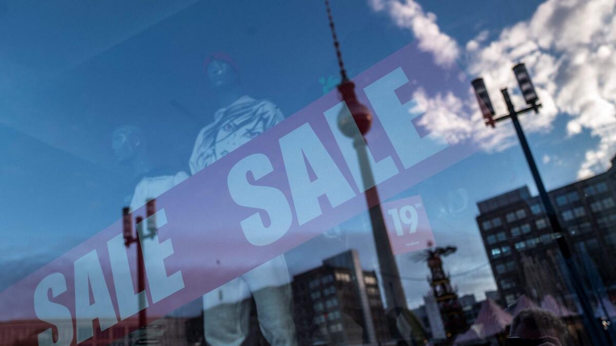 Berlin's TV tower is reflected in the window of a clothing store displaying a sale sign at Alexanderplatz. — AFP