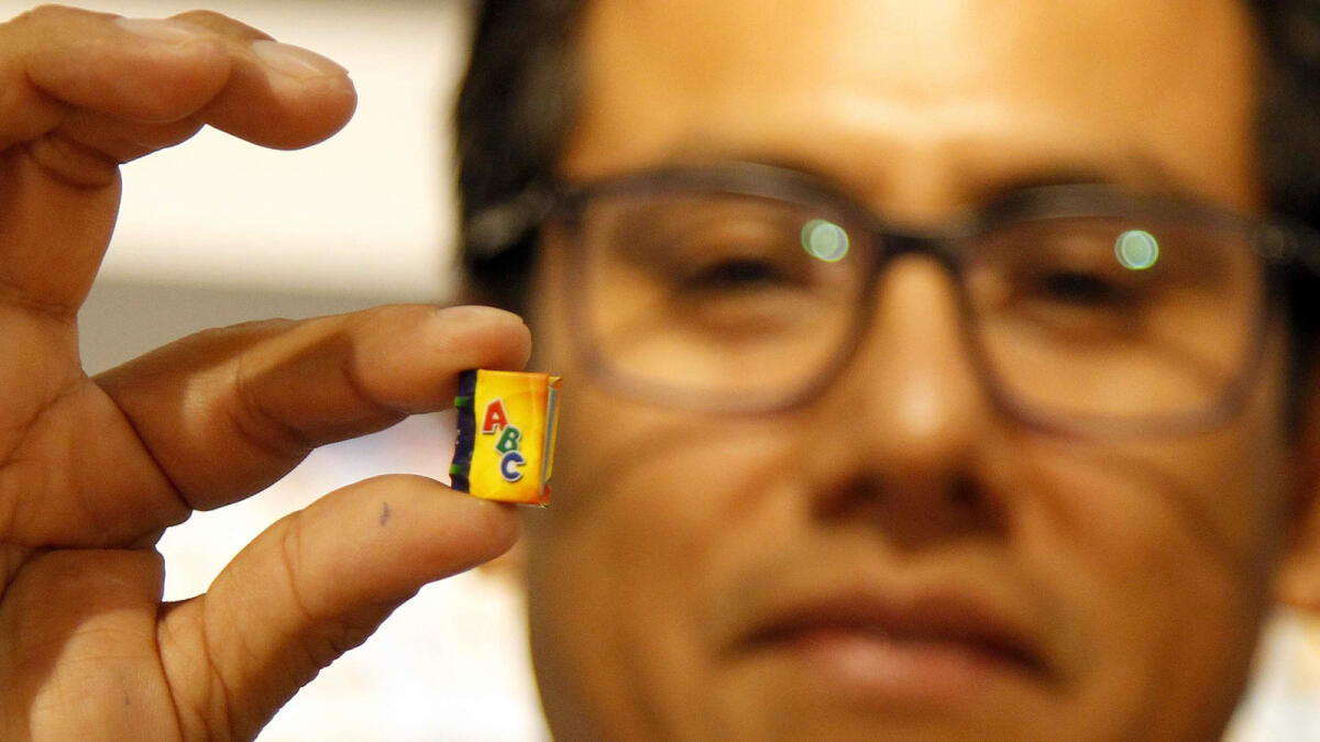 A man shows one of the smallest books in the world.– Photo by M.Sajjad/Khaleej Times