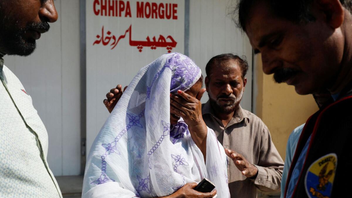 Relatives comfort each other as they mourn the death of Ajmal Maseh, who was killed in yesterday's attack on a police station in Karachi, Pakistan. — Reuters