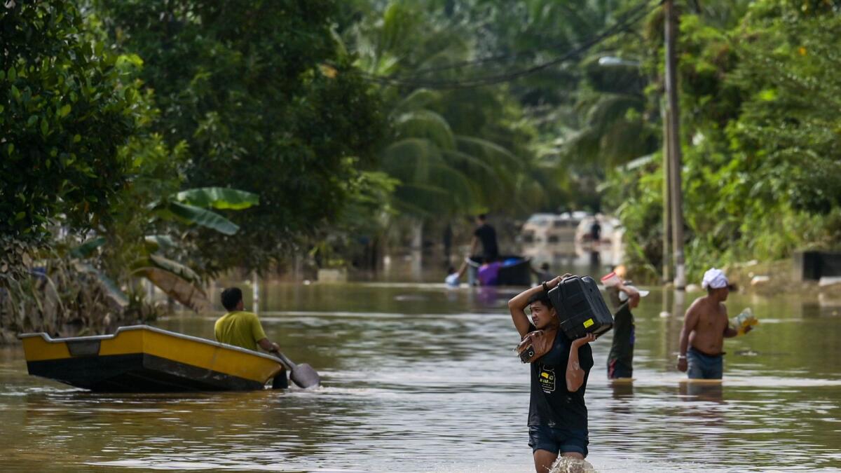 Residents walk along a road submerged by floodwaters in Mentakab in Malaysia's Pahang state on January 8, 2021, following heavy rains. — AFP photo