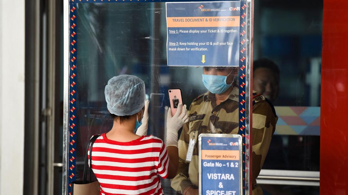 A security personnel checks the documents of a passenger standing behind a shield at the Indira Gandhi International airport. Photo: AFP