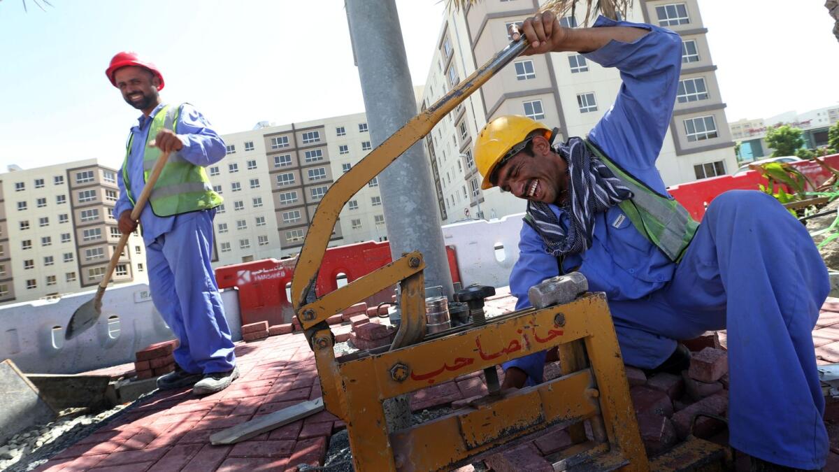 Workers sharing a light moment at a construction site in Dubai. — File photo