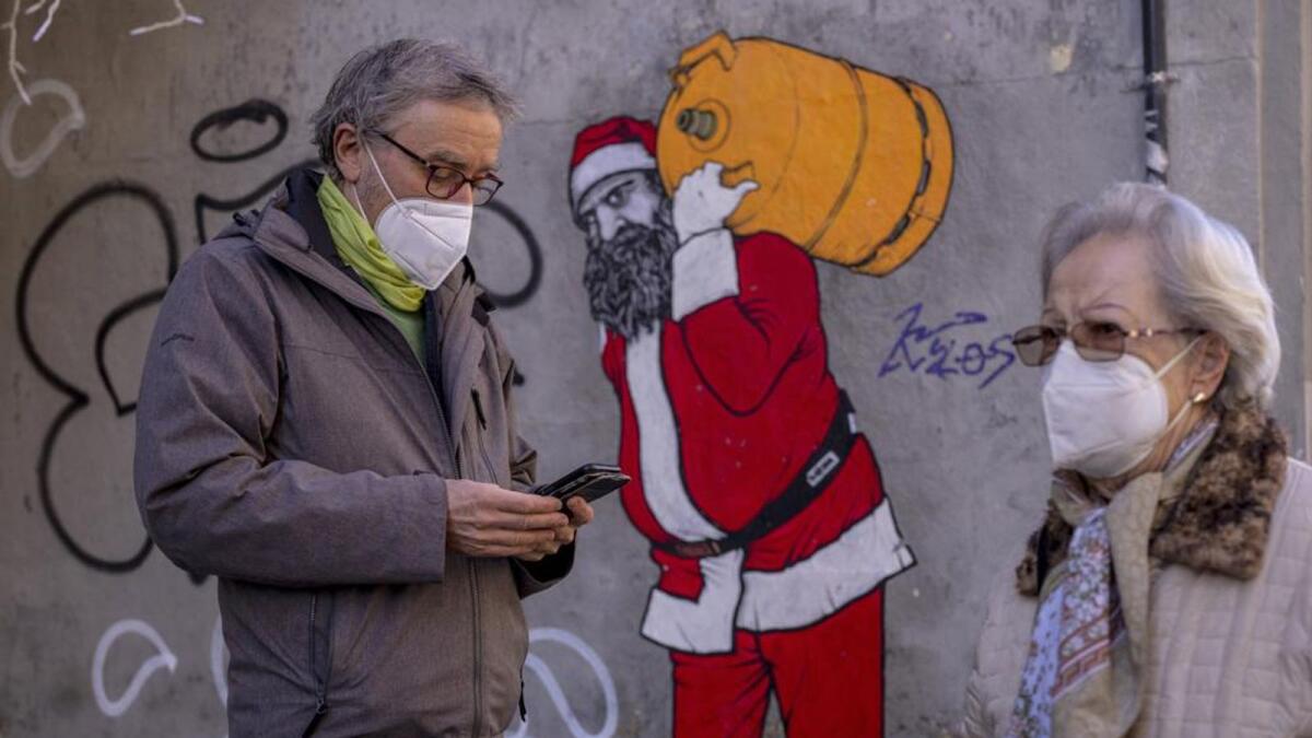 A man and woman wearing FFP2 masks to curb the spread of Covid-19 are seen in front of a mural depicting Santa Claus, in Madrid, Spain. — AP