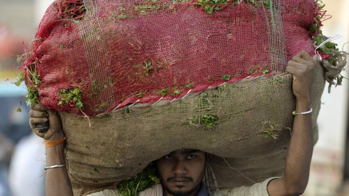 An Indian man carries a sack of vegetables at the wholesale market in Mumbai on January 28, 2017. India's government is expected to ramp up spending in its latest budget, seeking to ease the pain from a ban on high-value banknotes that slammed the brakes on the world's fastest-growing major economy. AFP