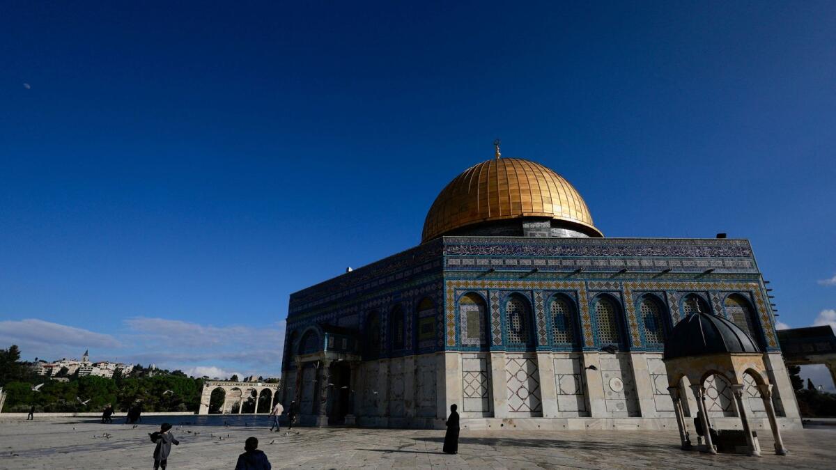Palestinians walk in front of the Dome of the Rock on Al Aqsa compound. — Reuters