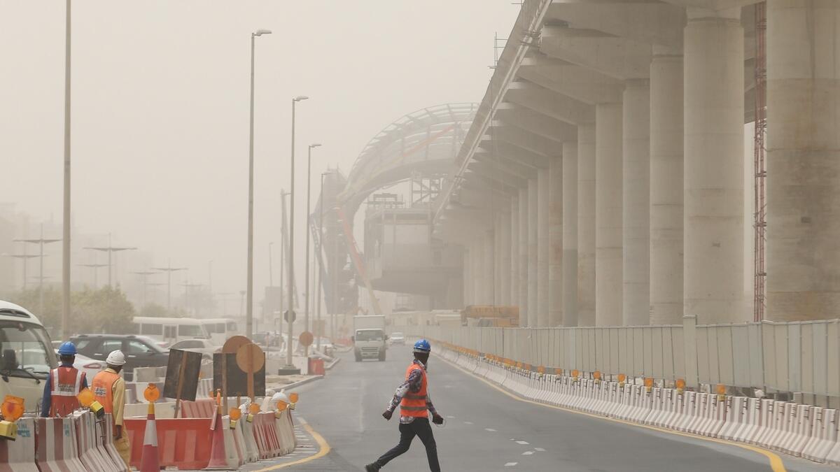 A person crossing a dusty street at the Discovery Gardens in Dubai.-Photo by Dhes Handumon