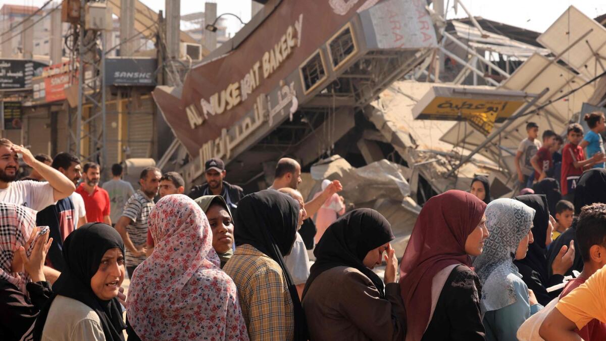 People queue for bread in front of a bakery that was partially destroyed in an Israeli strike, in the Nuseirat refugee camp in the central Gaza Strip, on November 2. — AFP