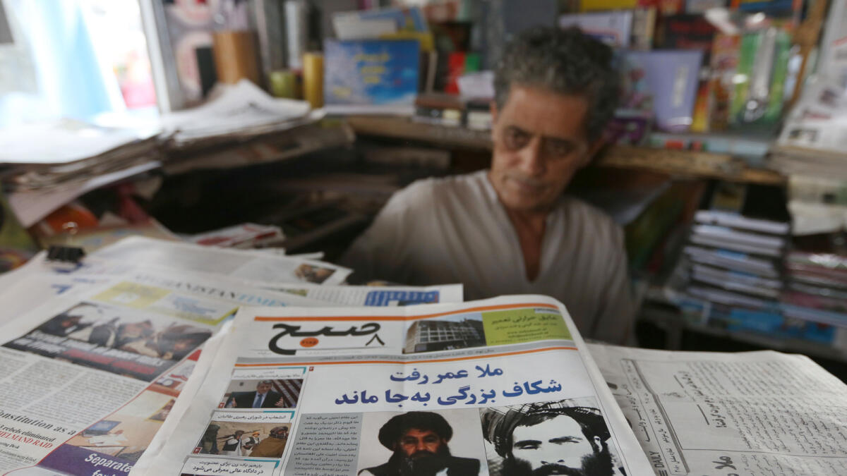 FILE - In this Aug. 1, 2015 file photo, an Afghan store clerk waits for customers at a news stand where local papers carry headlines about the new leader of the Afghan Taliban, Mullah Akhtar Mohammad Mansoor, in Kabul, Afghanistan. Afghanistan?s Taliban are closing ranks around their new leader after months of infighting that followed the death of Mullah Mohammad Omar, which could allow the insurgents to speak with one voice in hoped-for peace talks but will also strengthen them on the battlefield. (AP Photo/Rahmat Gul)
