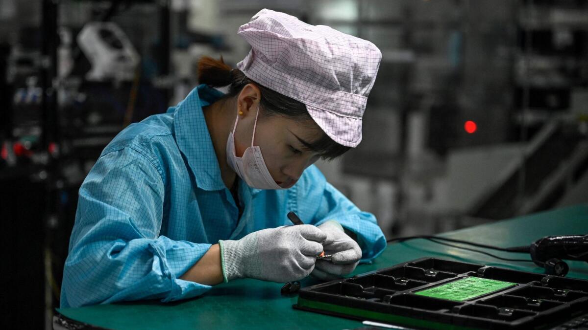 An employee working on a smartphone production line at Oppo factory in Dongguan, in China's southern Guangdong province. Factory output and retail sales in China edged up in July but were weaker than analysts' expectations, official data showed on August 15, 2022, as a Covid-19 resurgence and property market jitters cast a pall over hopes for a stronger economic recovery. — AFP