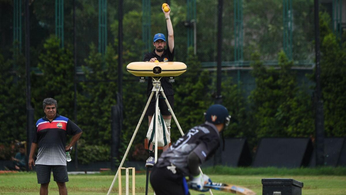 Evan McCall (centre), a trainer for the Philippines national cricket team, operating a bowling machine during a team training session in Manila. (AFP)