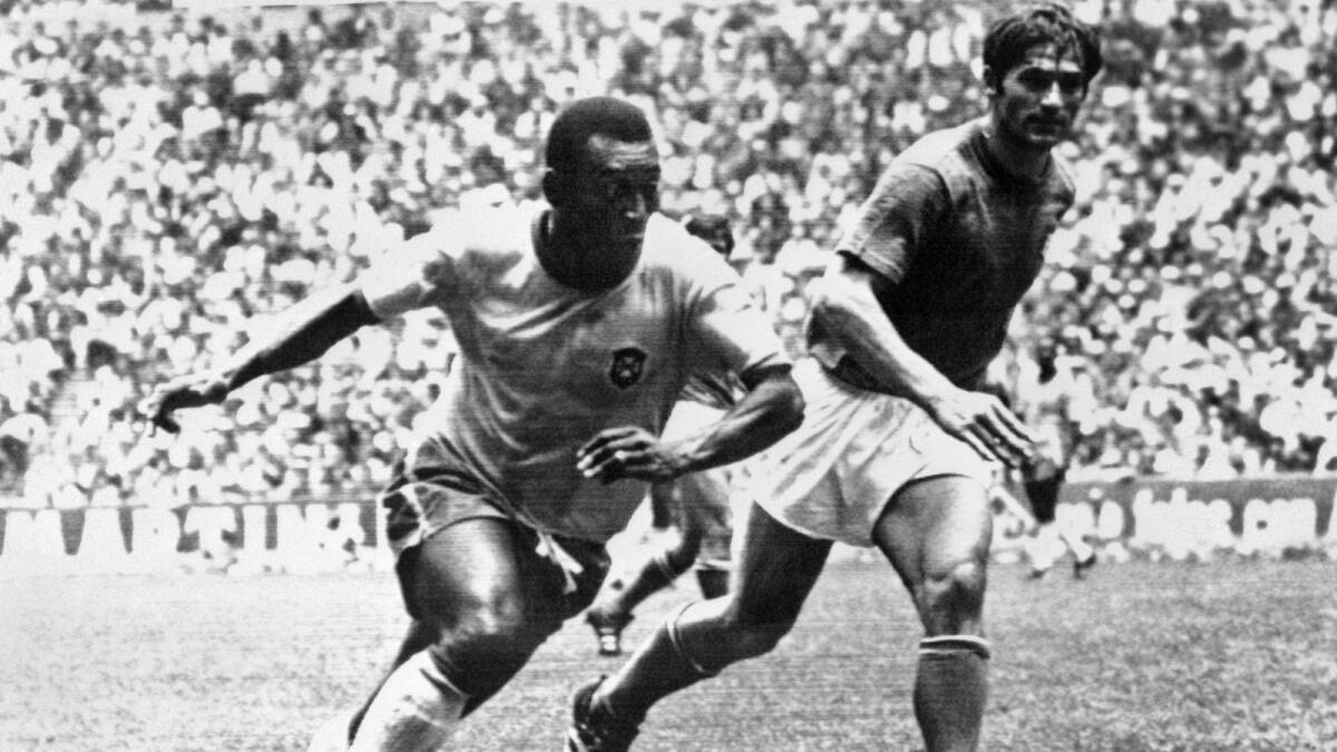 Pele (L) dribbles past Italian defender Tarcisio Burgnich during the World Cup final in Mexico City in 1970. - AFP file