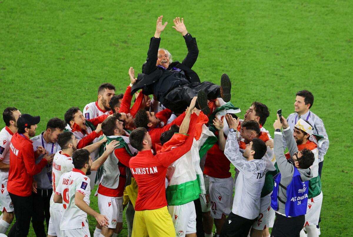 Tajikistan players celebrate with coach Petar Segrt after the match. — Reuters