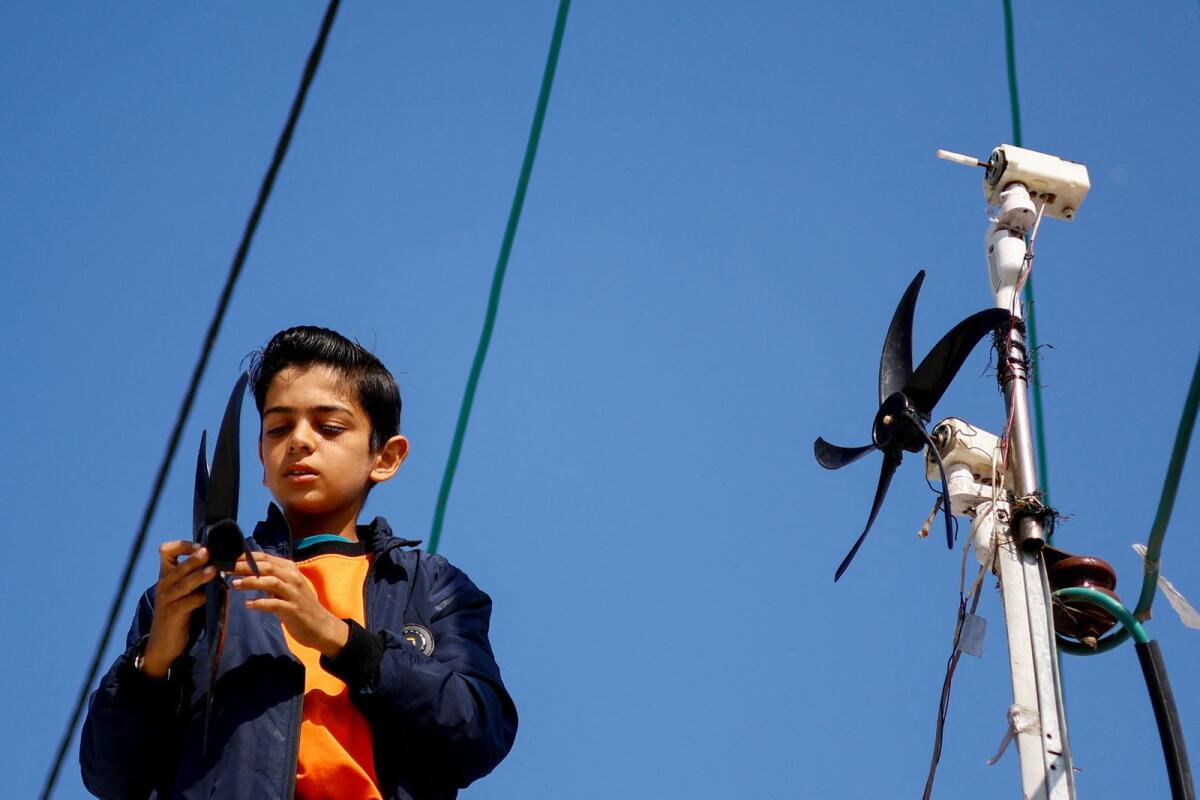Displaced Palestinian teenager Hussam Al Attar, nicknamed by people 'Newton', works on wind turbines, that he uses to light up his shelter during power cut, at a tent camp in Rafah. — Reuters