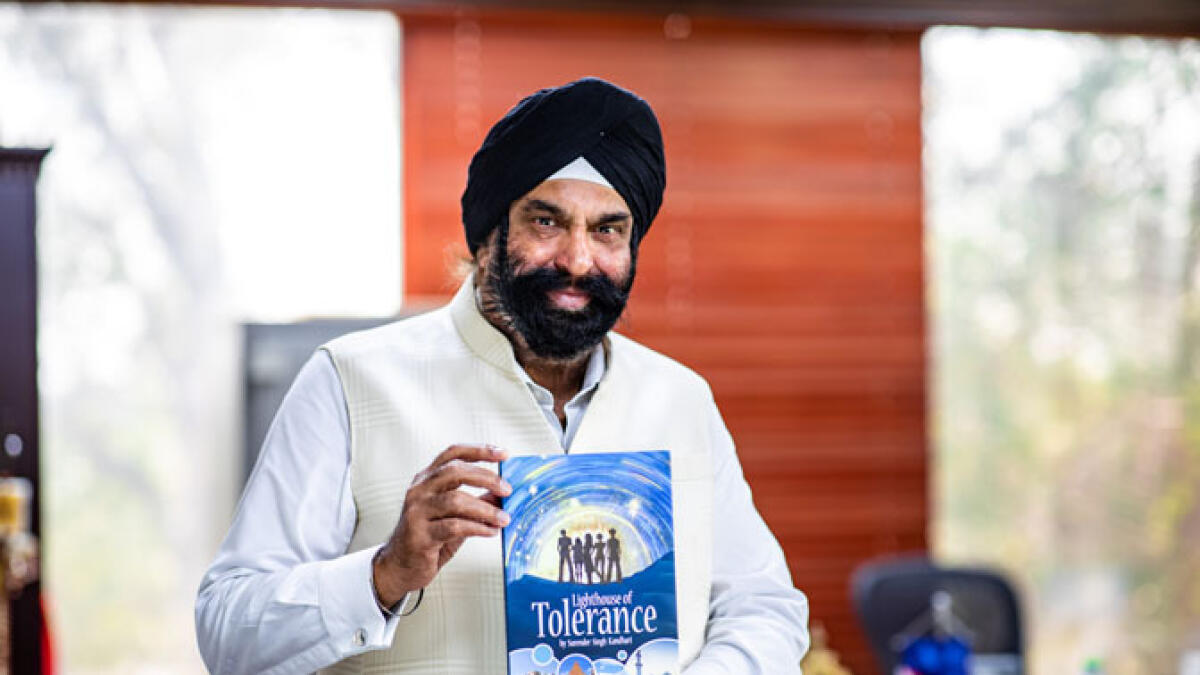 Surender Singh Kandhari poses with copies of his upcoming book, Lighthouse of Tolerance