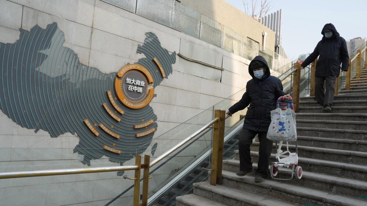 Residents walk through a partially shuttered Evergrande commercial complex in Beijing on Monday. Chinese property developer China Evergrande Group on Monday was ordered to liquidate by a Hong Kong court, after the firm was unable to reach a restructuring deal with creditors. — AP