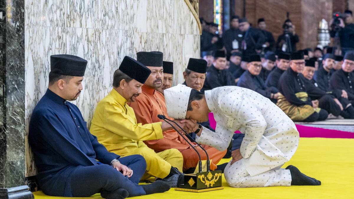 Prince Abdul Mateen, right, touching his forehead on his father's hand after his solemnization at Sultan Omar Ali Saifuddien Mosque in Bandar Seri Begawan, Brunei. — AP