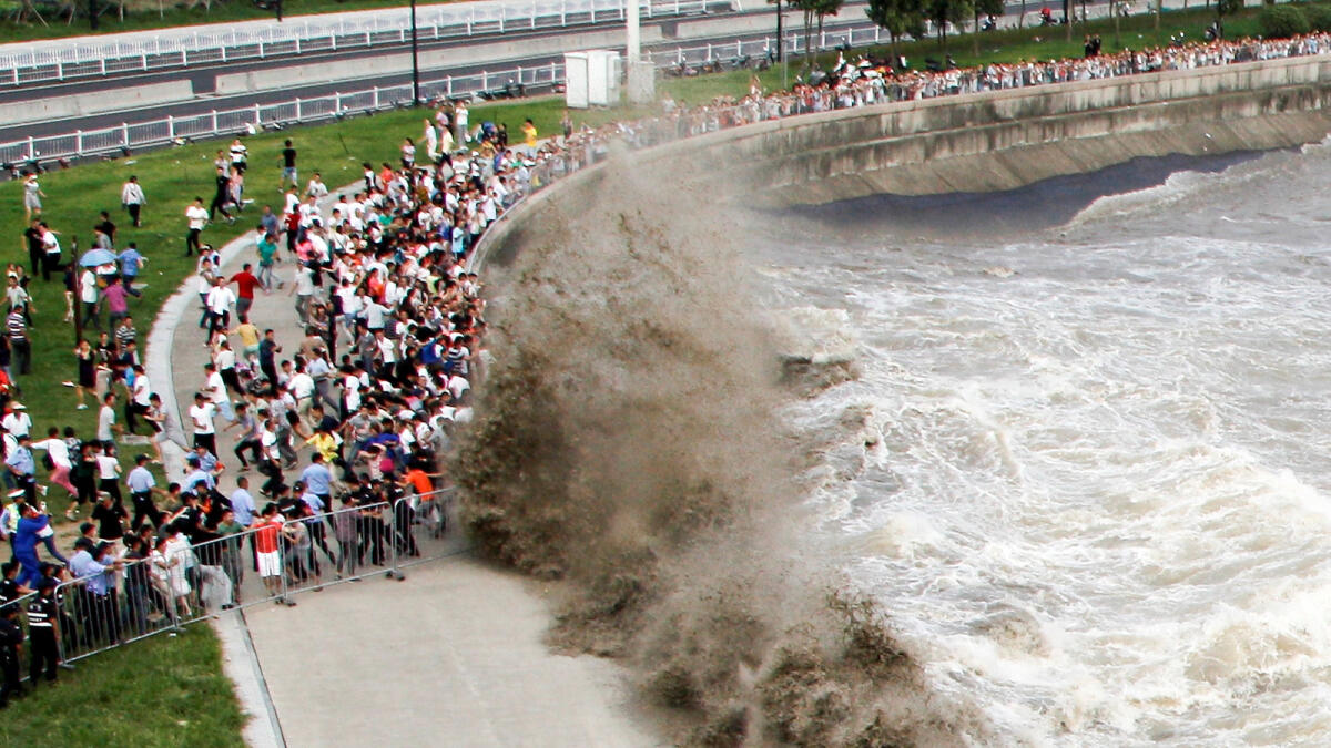 People run away from waves as they watch tidal bore in Hangzhou, Zhejiang Province, China, September 19, 2016. Reuters