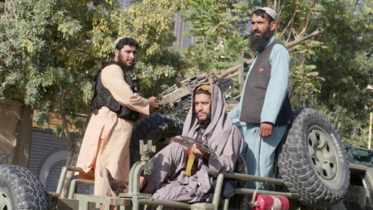 Taliban fighters stand on the back of a vehicle as they conduct a 'house to house' inspection. — AFP