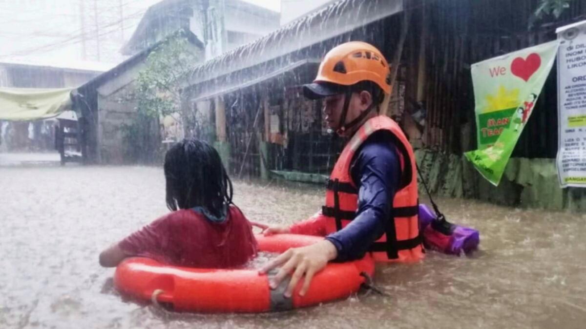 In this handout photo provided by the Philippine Coast Guard, a rescuer assists a girl as they wade through flooding caused by Typhoon Rai in Cagayan de Oro City, southern Philippines. — AP