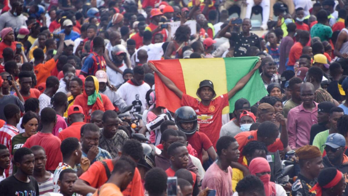 A supporter holds up a Guinean National Flag as exiled activists arrive in Conakry. — AFP