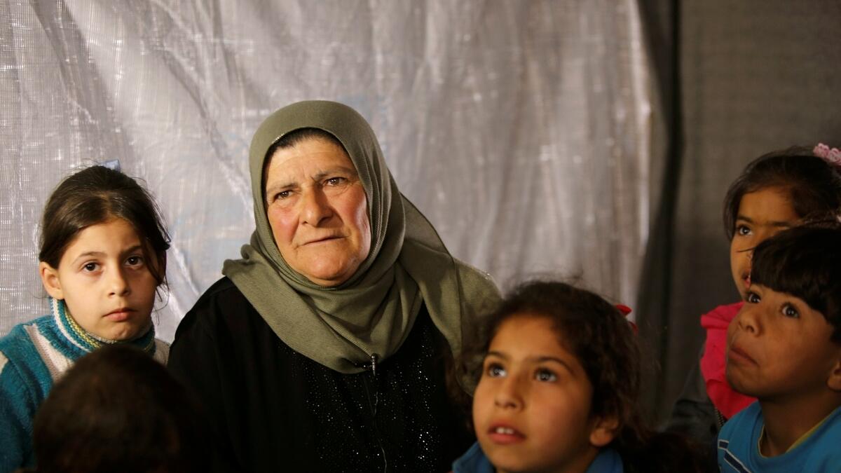 Amira Gharmoush sits with her grandchildren inside a tent in Herjelleh shelter in Damascus countryside, Syria.- Reuters