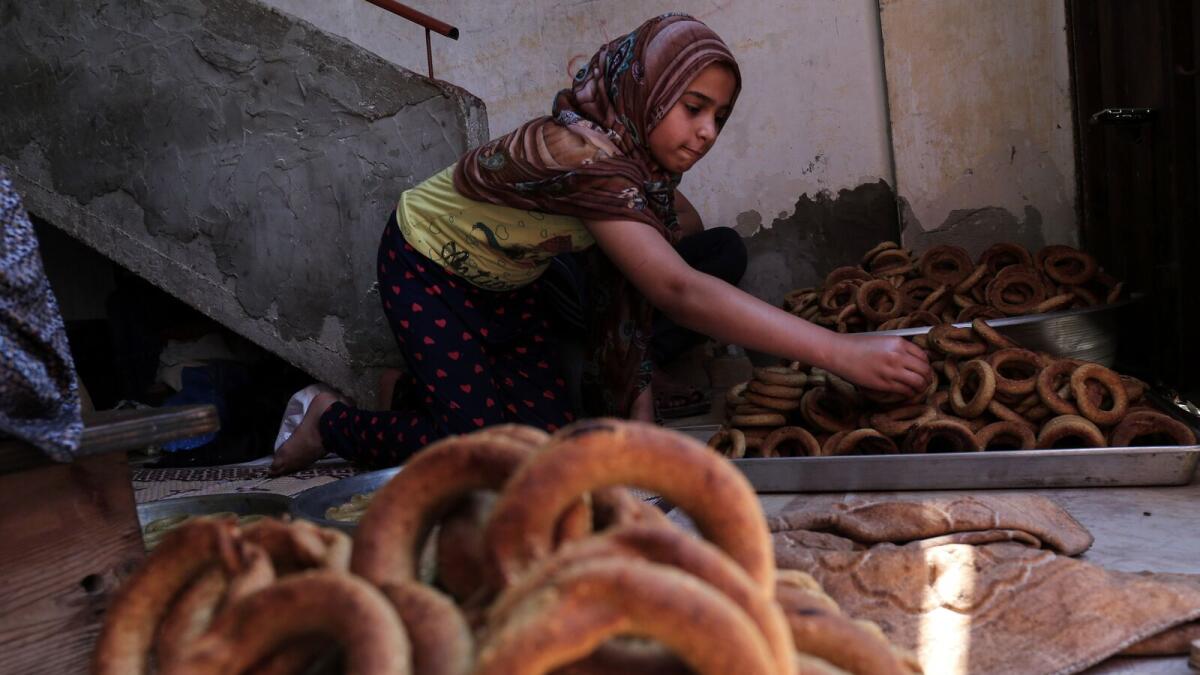 A Palestinian girl makes traditional date-filled cookies with her family in preparation for the Eid Al Fitr holiday at their home in Rafah.