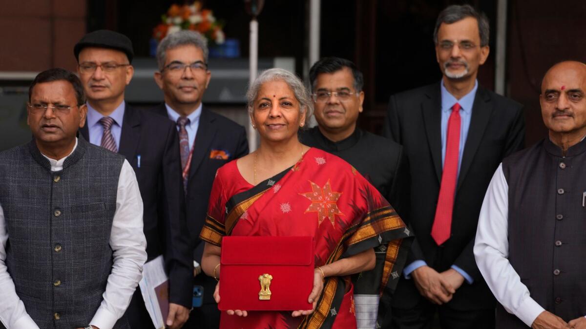 Indian Finance Minister Nirmala Sitharaman, in red, poses for the media holding a pouch containing a digital tablet as she leaves her office along with her colleagues for President's house before presenting the federal budget for the financial year 2023-24 in the Parliament in New Delhi on Wednesday. - AP
