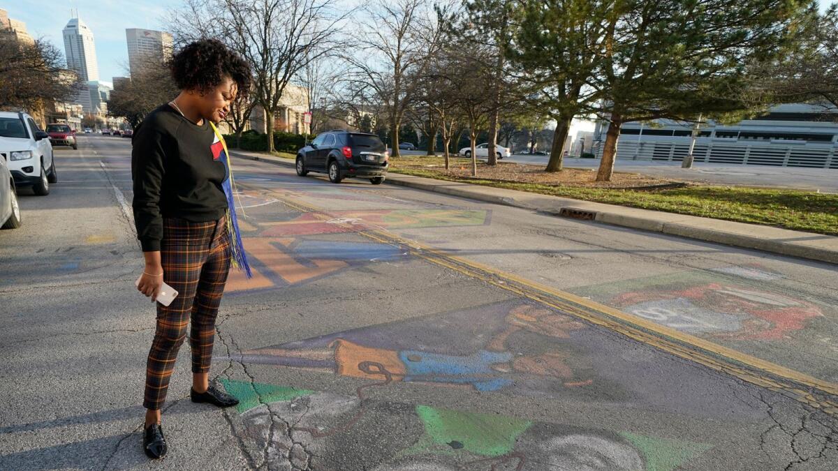 Malina Jeffers looks at the Black Lives Matter street mural stretching across Indiana Avenue, on Dec. 10, 2020, in Indianapolis.
