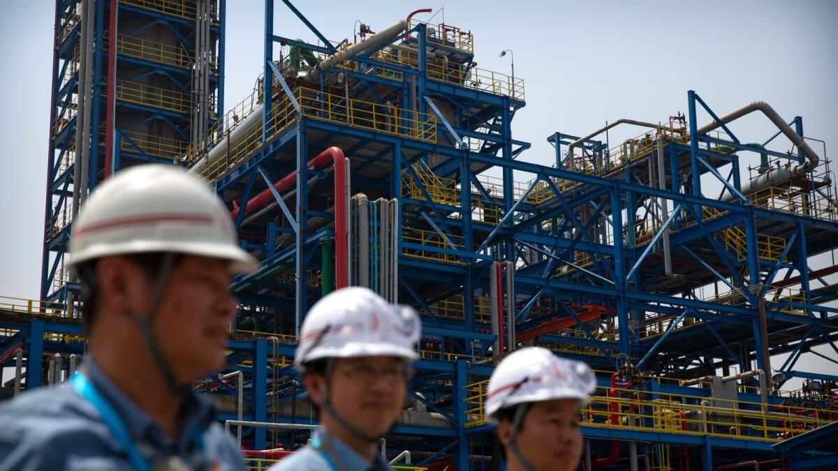 Workers stand near facilities for producing polypropylene at the Sinopec Yanshan Petrochemical Company on the outskirts of Beijing. The forecast for China was also revised lower, by 0.2 percentage points, to 7.8 per cent. — AP file