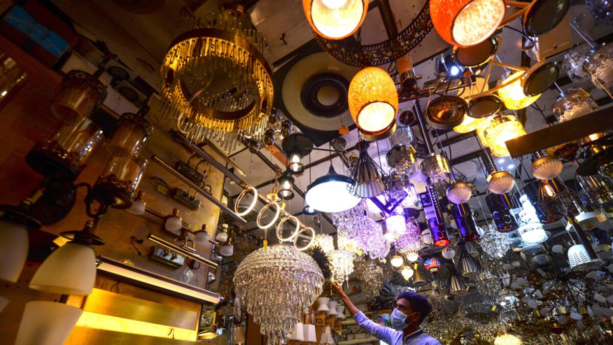 A shopkeeper cleans the dust off a chandelier at a shop in Dhaka, Bangladesh. Photo: AFP