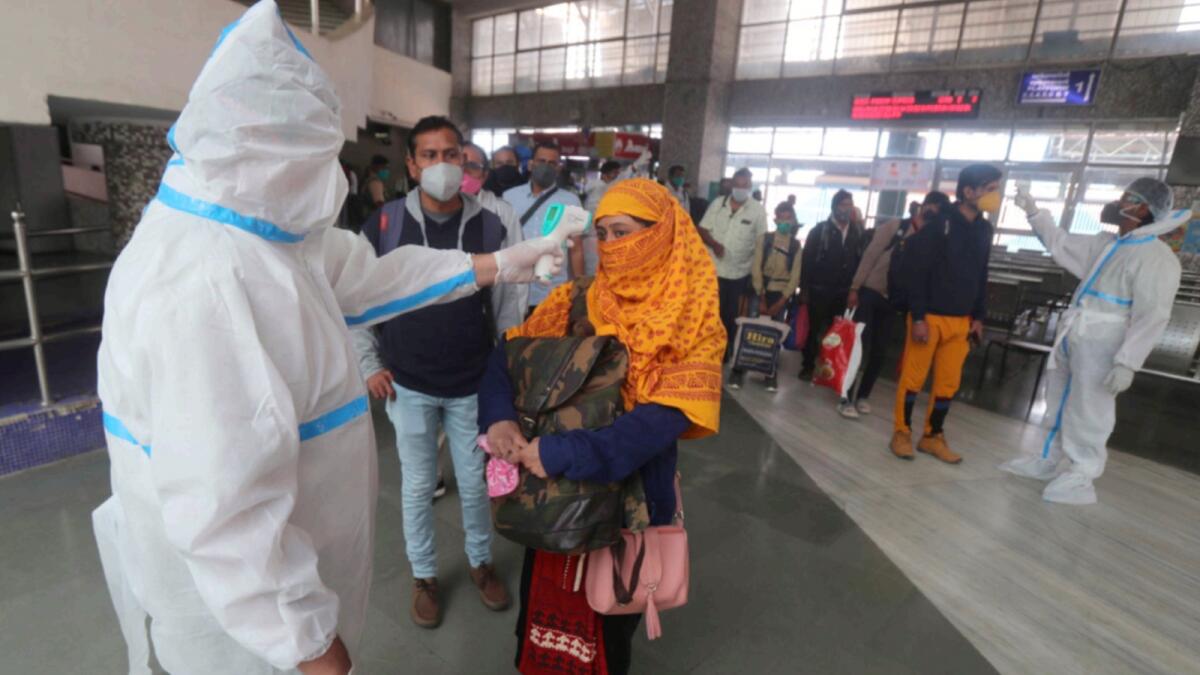 Health workers check the temperatures of a passengers at Bandra train station in Mumbai. — AP