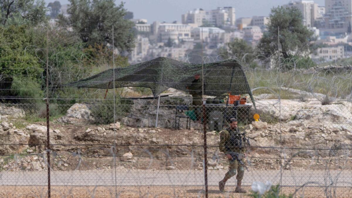 An Israeli soldier guards an opening in the West Bank separation barrier that was reinforced with barbed wire to prevent Palestinians from crossing into Israel. — AP file