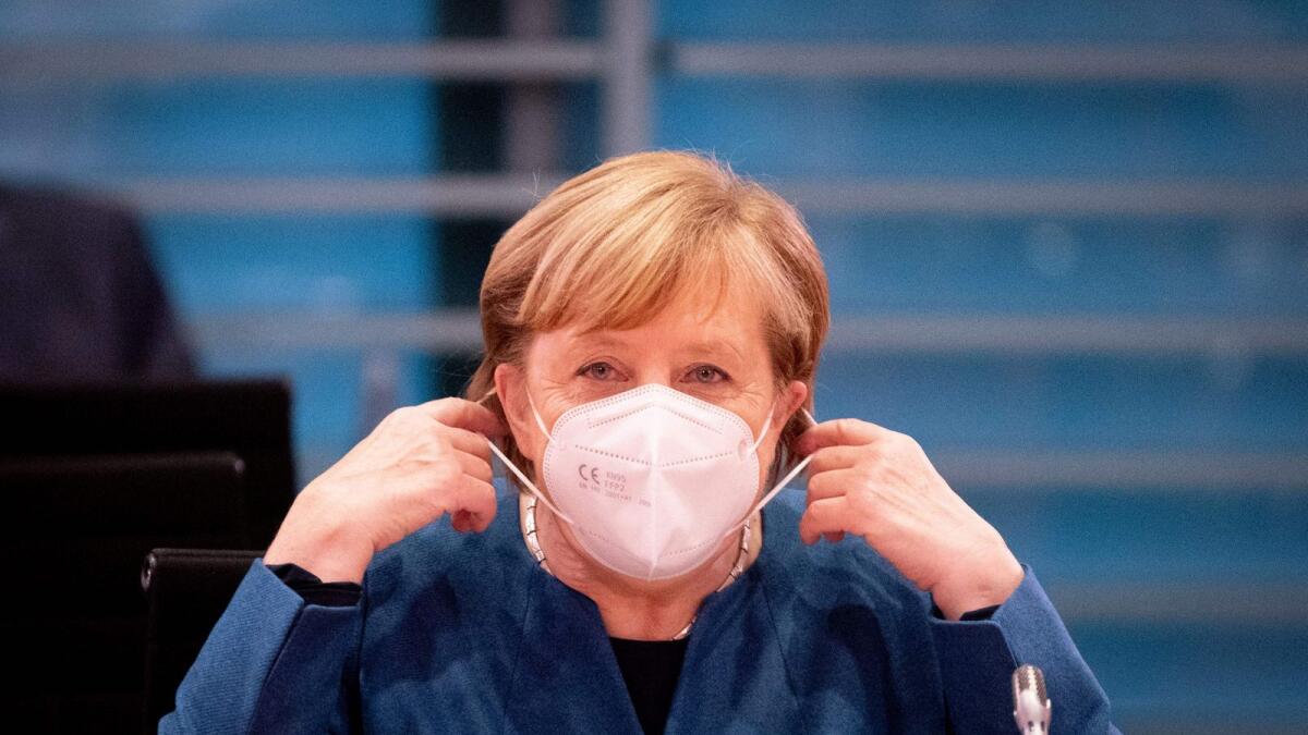 German Chancellor Angela Merkel takes off her face mask as she arrives to lead the weekly cabinet meeting at the Chancellery in Berlin on Wednesday.