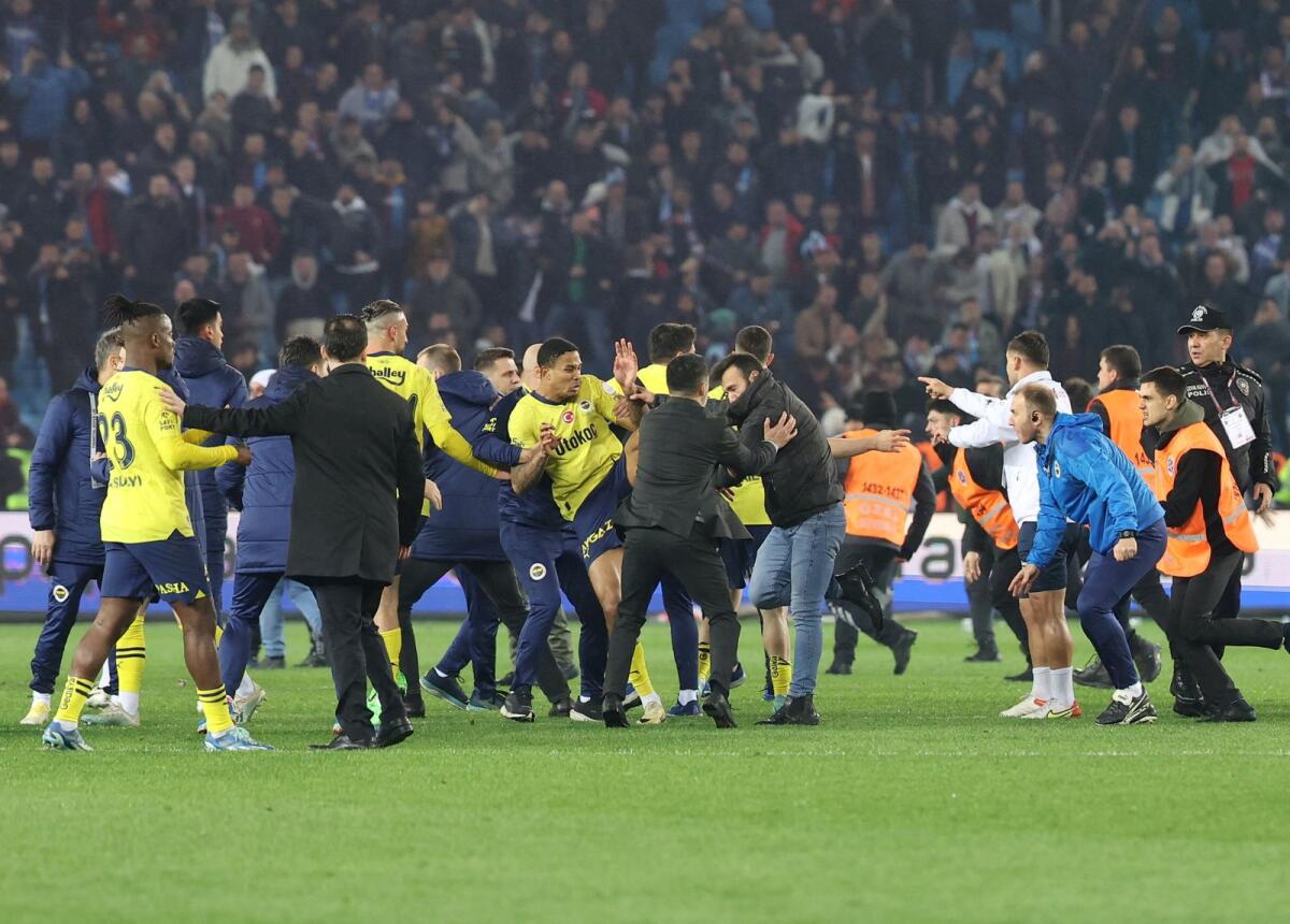 Trabzonspor fans invade the pitch and clash with Fenerbahce players and security staff after the match. — Reuters