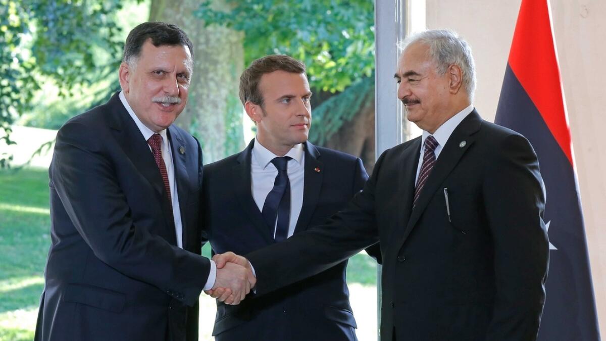 Libyas Prime Minister Fayez al-Sarraj of the UN-backed government, left, and General Khalifa Hifter of the Egyptian-backed commander of Libyas self-styled national army shake hands as Frances President Emmanuel Macron stands between after a declaration