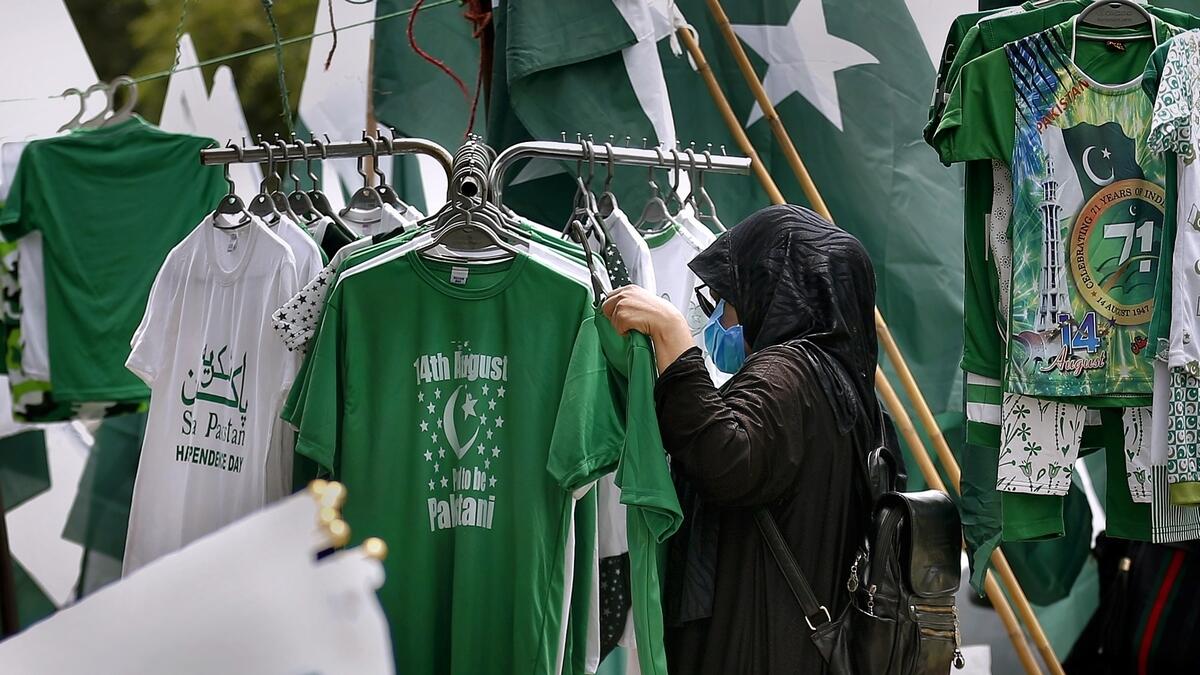 A woman shops shirts with words 'Happy Independence Day!' at a market ahead of Independence Day celebrations, in Islamabad. AP photo