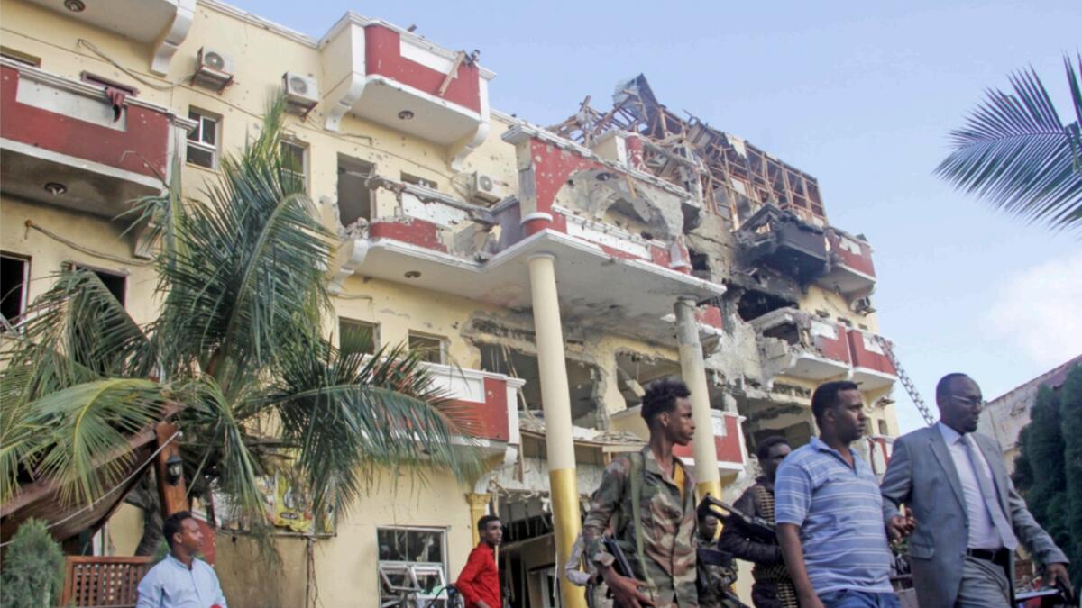 Security forces and others walk in front of the damaged Hayat Hotel in the capital Mogadishu. — AP