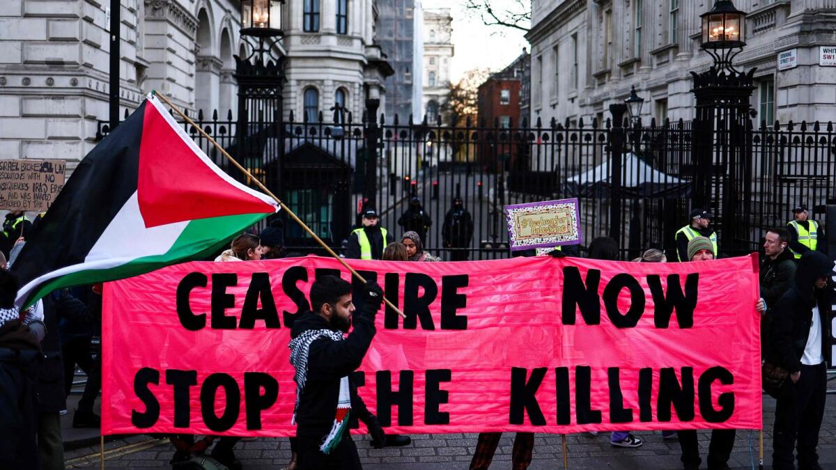 Protesters hold Palestinian flags and banners in front of Downing Street on Saturday. — AFP