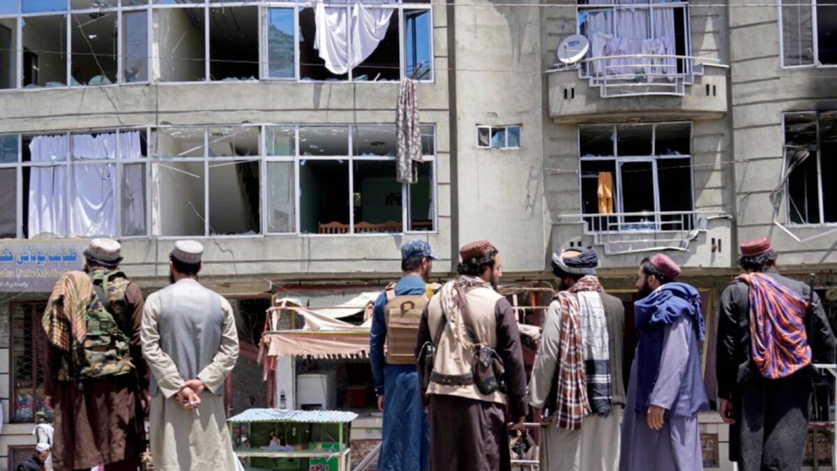 Taliban fighters gather at the site of an explosion in front of a Sikh temple in Kabul. — AP
