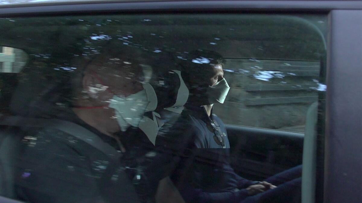 This screen grab taken from AFPTV shows Serbia's Novak Djokovic (right) wearing a face mask as he arrives at the lawyer's office on Sunday. (AFP)