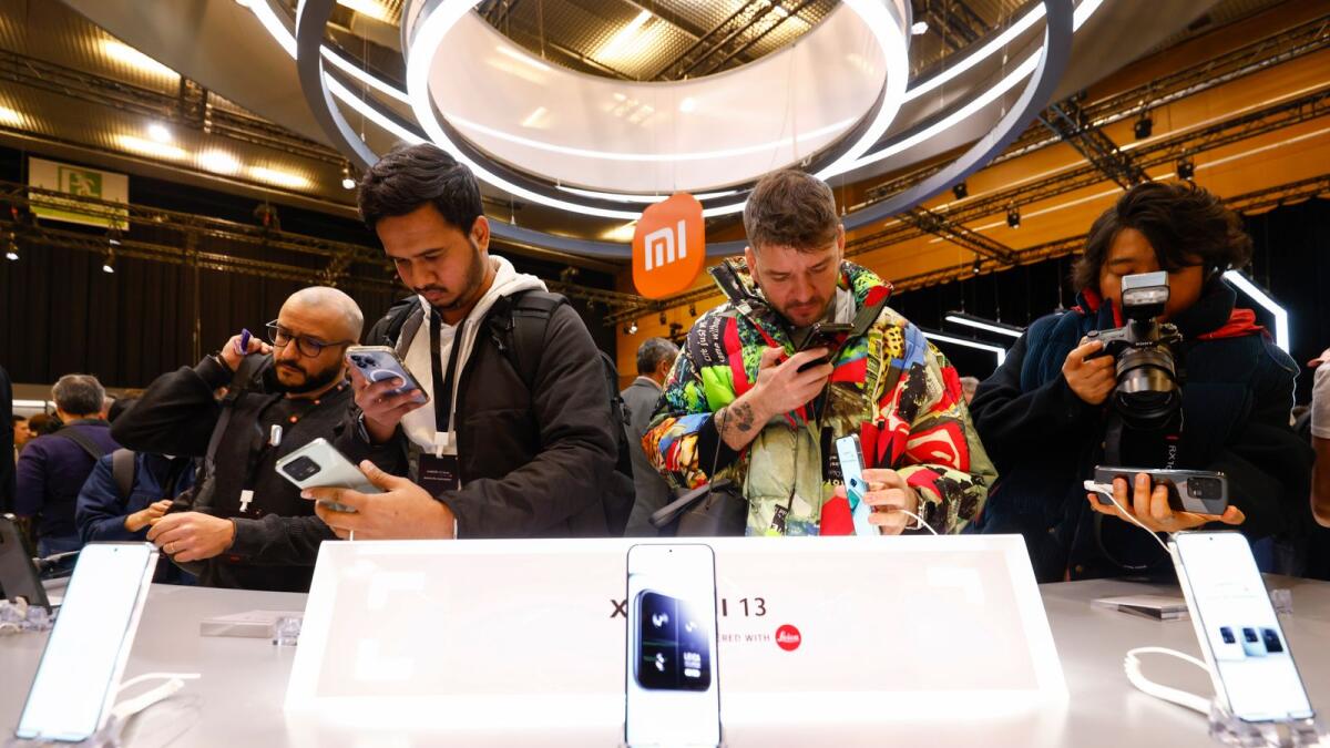 Visitors take pictures of Xiaomi 13 mobile phone models at the Xiaomi booth before the Mobile World Congress 2023 in Barcelona. — AP