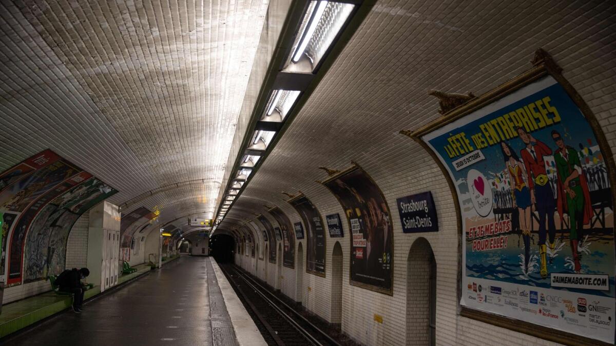 A man sits on the deserted platform of a metro station, on October 17, 2020 in Paris, at the start of a nighttime curfew implemented to fight the spread of the Covid-19 pandemic caused by the novel coronavirus.