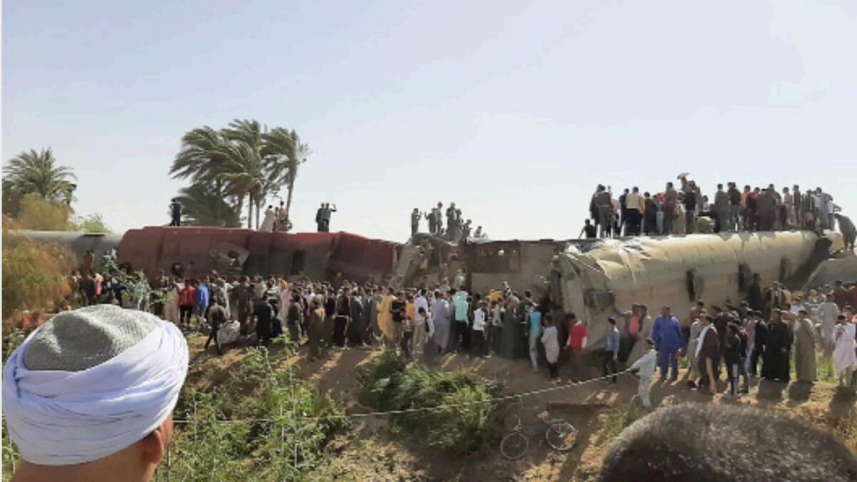 People gather around the wreckage of two trains that collided in the Tahta district of Sohag province in Egypt. — AFP