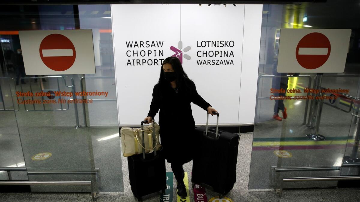 A woman walks through the door at the arrival terminal of the Chopin airport, amid the coronavirus disease (COVID-19) outbreak, in Warsaw, Poland, December 21, 2020.