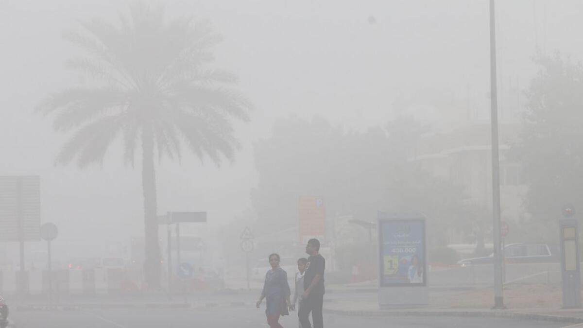 A family crosses the street on a foggy morning in Garhoud in Dubai.