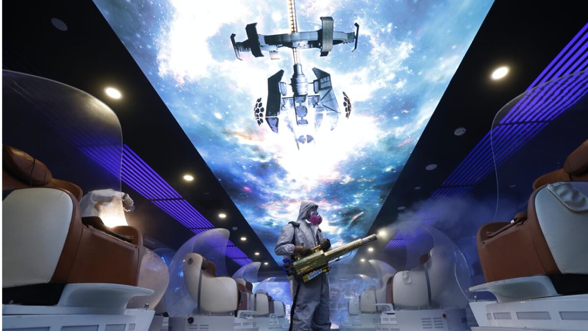 A volunteer with the Blue-Sky Rescue team performs disinfecting of the virtual reality theater in a cinema before it reopens for business in Beijing.  Theaters in China, the world’s second largest movie market, this week reopened from the coronavirus shut down with theaters limited to 30% capacity. Photo: AP