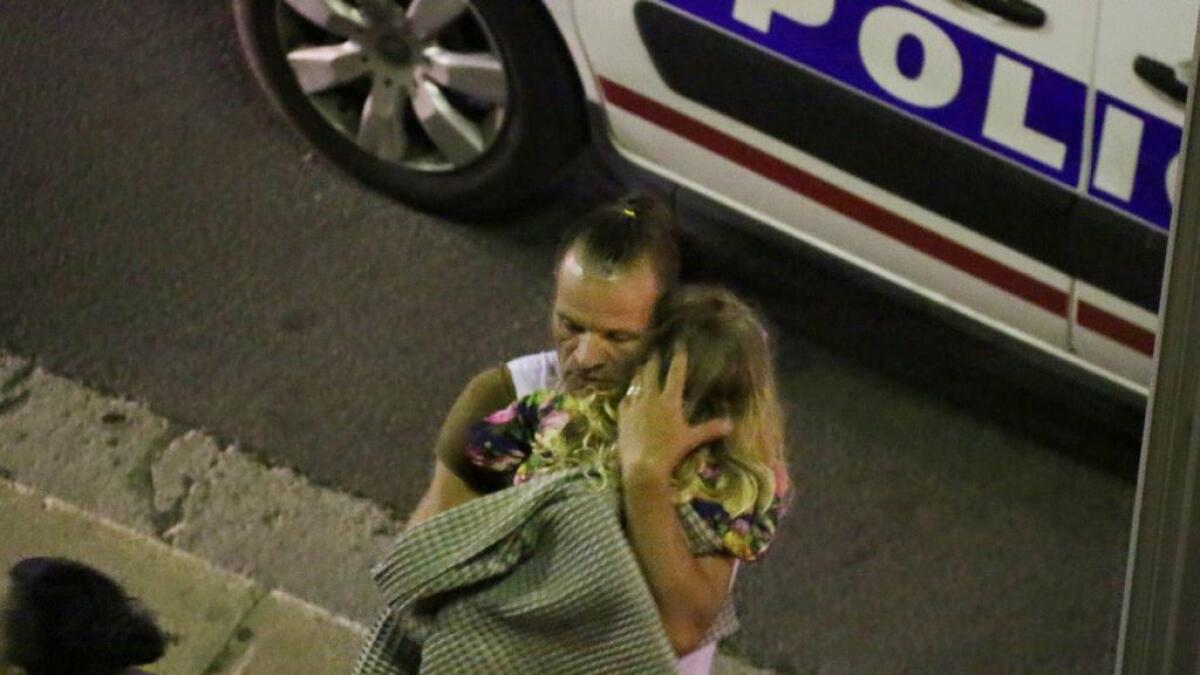 A man holds a child after a truck plowed through Bastille Day revelers in the French resort city of Nice, France, 