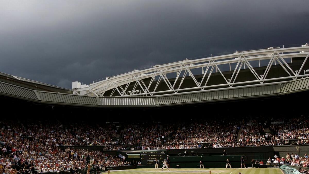 Dark clouds drift over centre court during the finals match between Roger Federer of Switzerland and Rafael Nadal of Spain at the Wimbledon tennis championships in London. - Reuters file